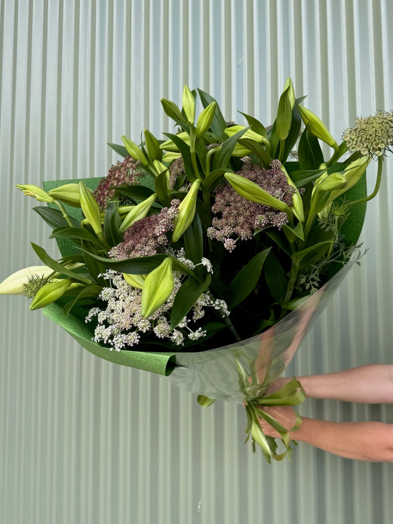 Bouquet of flowers held by a person against a light green background