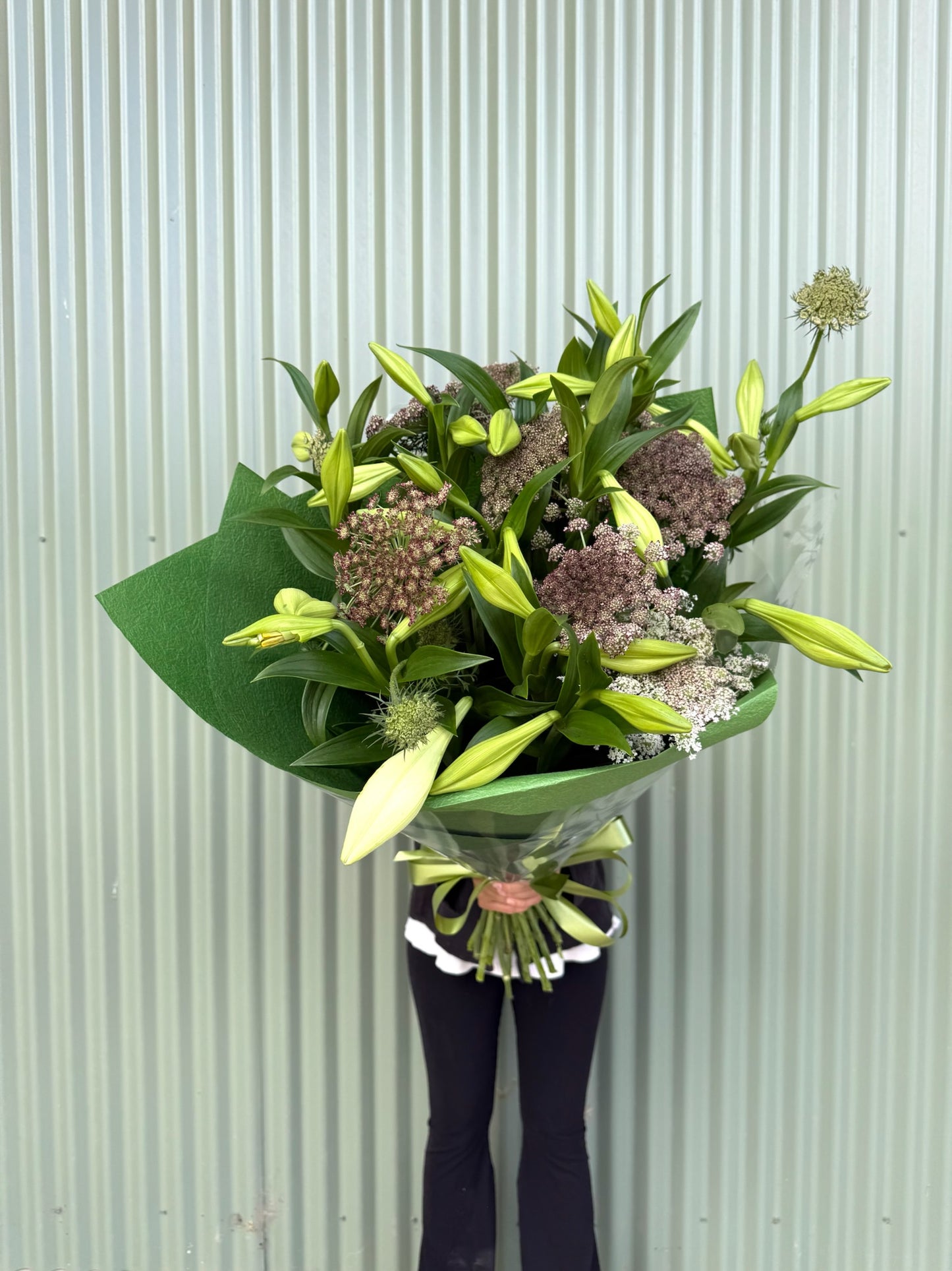 Bouquet of flowers held by a person against a light green background